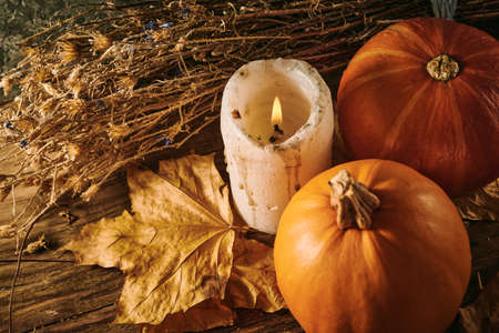 Autumn pumpkins and a candle on a wooden backgroundの写真素材