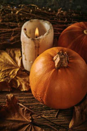 Autumn pumpkins and a candle on a wooden backgroundの写真素材
