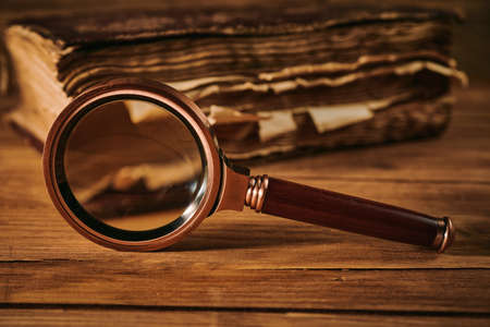 Magnifying glass and the ancient magic book on wooden tableの写真素材