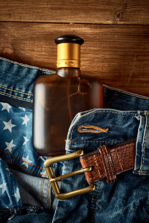 A bottle of perfume for men on denim jeans background, male style, the scent of a manの写真素材