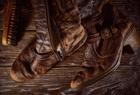 Vintage distressed leather shoes, grunge brown leather boots, rough wooden backgroundの写真素材