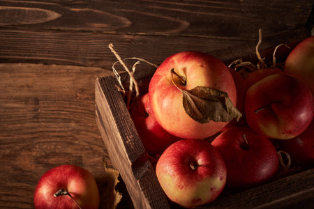 Ripe red apples in a wooden box on a wooden background.の写真素材