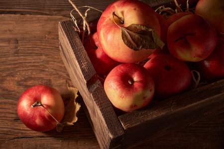 Ripe red apples in a wooden box on a wooden background.の写真素材
