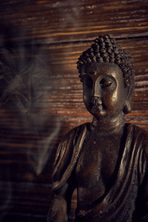 Buddha statue with smoke on a wooden background. Selective focus.の写真素材