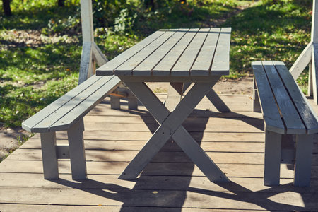 Wooden picnic table and benches in the park on a sunny dayの写真素材