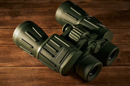 Green binoculars on a wooden background. Selective focus. Toned.の写真素材