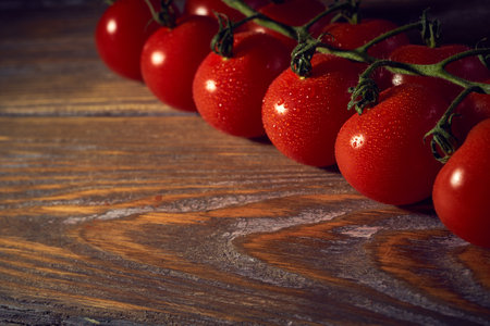 Cherry tomatoes on a branch on a wooden background. Toned.の写真素材