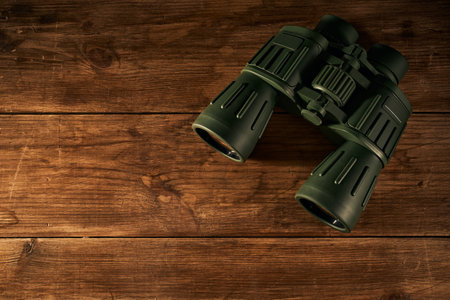 Green binoculars on a wooden background. View from above.の写真素材