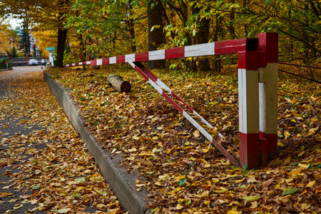 Autumn landscape with red and white barriers on the road in the park