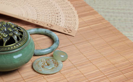Chinese incense burner, traditional nephrite jewelry and on the bamboo mat background. still-life. copy spaceの写真素材