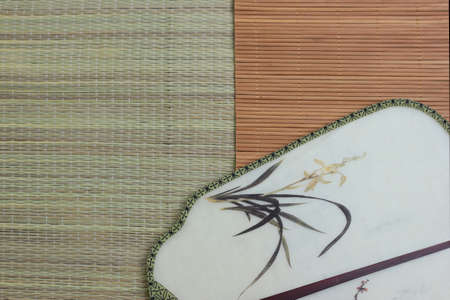 Chinese traditional fan on the bamboo mat background. still-life. copy spaceの写真素材