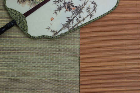 Chinese traditional fan on the bamboo mat background. still-life. copy spaceの写真素材