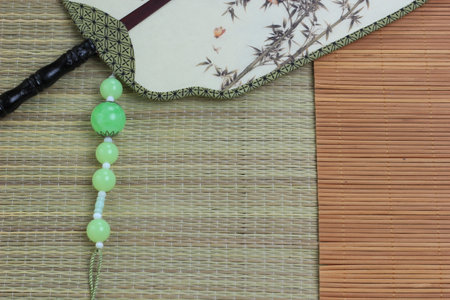 Chinese traditional fan on the bamboo mat background. still-life. copy spaceの写真素材