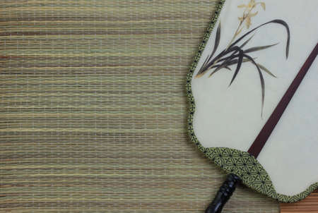 Chinese traditional fan on the bamboo mat background. still-life. copy spaceの写真素材