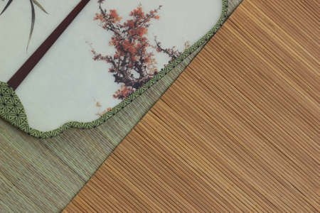 Chinese traditional fan on the bamboo mat background. still-life. copy spaceの写真素材