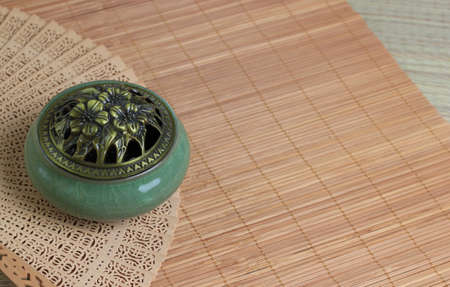 Ð¡hinese incense burner and fan on the bamboo mat background.の写真素材