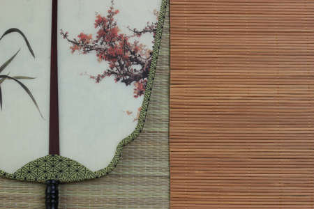 Chinese traditional fan on the bamboo mat background. still-life. copy spaceの写真素材
