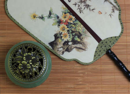 Ð¡hinese incense burner and fan on the bamboo mat background.の写真素材