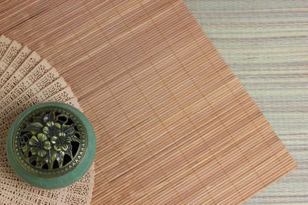 Ð¡hinese incense burner and fan on the bamboo mat background. copy space.の写真素材