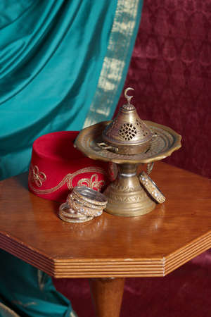 Still life in turkish Muslim ottoman oriental style. censer, fez, bracelets on the table. Muslim...