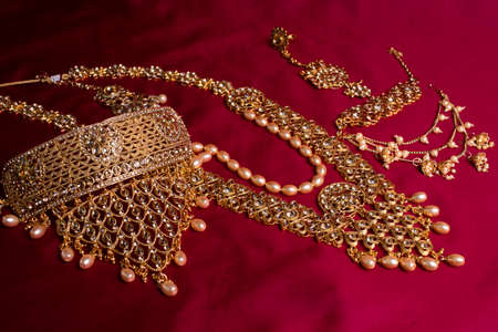 Indian traditional gold Indian wedding women's jewelry on red sari background. Close-up. Still-life.の写真素材