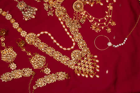 Indian traditional gold Indian wedding women's jewelry on red sari background. Close-up. Still-life.の写真素材