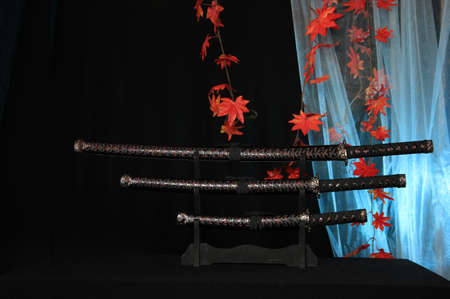 Japanese sword Katana, wakizashi and tanto on stand. on red autumn leaves backgroundの写真素材