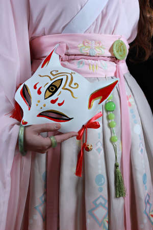 Woman wearing kimono or hanfu and a fox mask. Traditional japanese fox masks called kitsune. Chinese, Japanese traditional concept.の写真素材