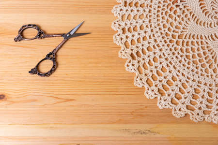 A knitted napkin and scissors on a wooden background. Needlework.の写真素材