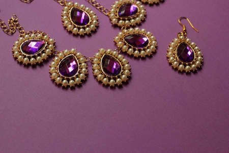 Indian female jewelry in gold and purple on a purple background.の写真素材