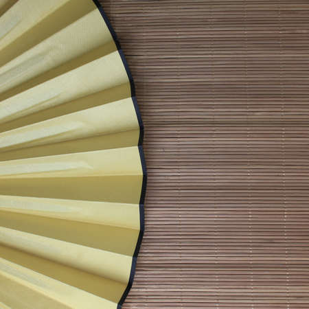 chinese yellow fan on bamboo mat background. still life.の写真素材