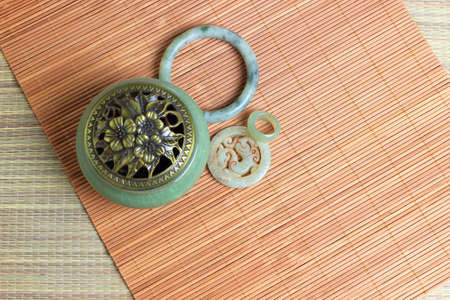Chinese incense burner, traditional nephrite jewelry and on the bamboo mat background. still-life. copy spaceの写真素材