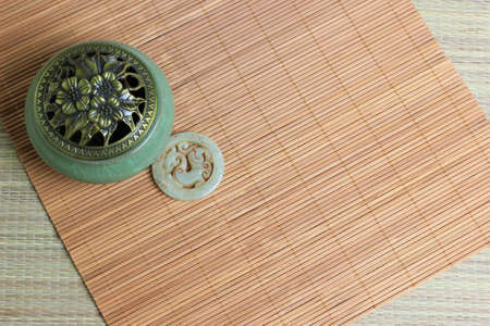 Chinese incense burner, traditional nephrite jewelry and on the bamboo mat background. still-life. copy spaceの写真素材