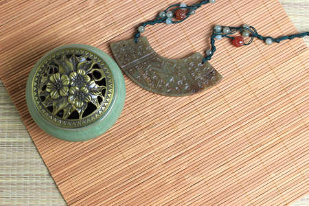 Chinese incense burner, traditional nephrite jewelry and on the bamboo mat background. still-life. copy spaceの写真素材