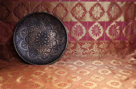 Bronze plate in oriental style on a background of dark red and gold, a magnificent century.の写真素材