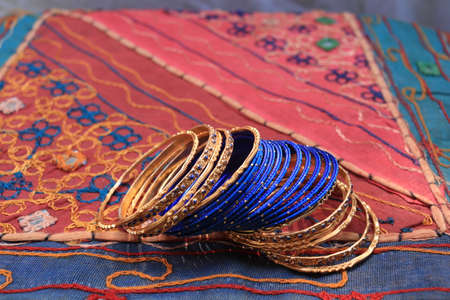 Indian blue bracelets on the background of a traditional patchwork carpet. Indian background.の写真素材