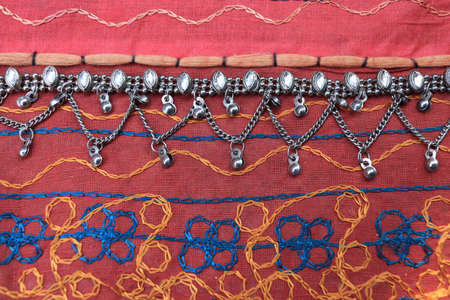 Indian silver anklets on the background of a traditional patchwork carpet. in indian background.