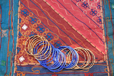 Indian blue bracelets on the background of a traditional patchwork carpet. Indian background.の写真素材