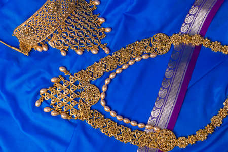 Indian traditional gold Indian wedding women's jewelry on blue saree background. Close-up. Still-life.の写真素材