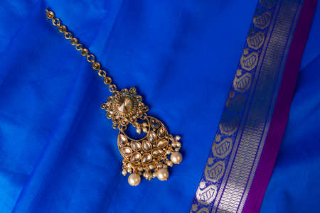 Indian traditional gold Indian wedding women's jewelry tika on blue saree background. Close-up. Still-life.の写真素材