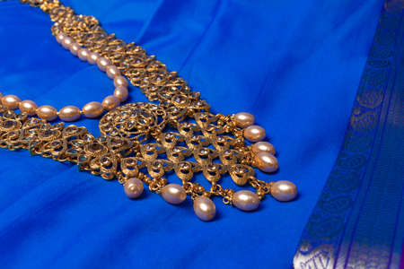 Indian traditional gold Indian wedding women's jewelry on blue saree background. Close-up. Still-life.の写真素材