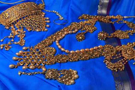 Indian traditional gold Indian wedding women's jewelry on blue saree background. Close-up. Still-life.の写真素材