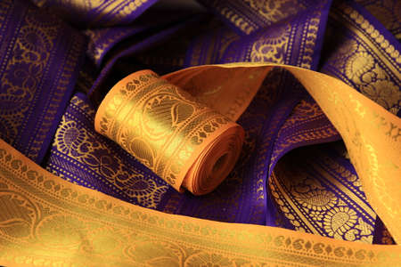 Purple violet and yellow Indian Sari border with gold paisley pattern. purple yellow background.の写真素材