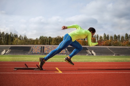 Afro-American man running around the stadium. Young sprinter on the track for jogging