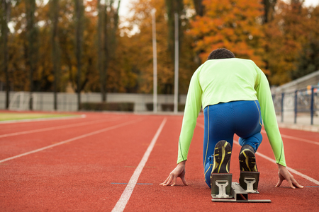 Young sporty man are ready to run on racetrack. Fit well formed people are at large nice modern...