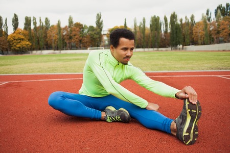 African runner stretching before workout. The guy preparing for training