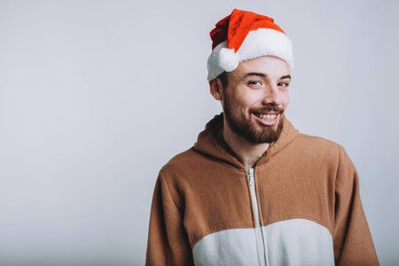 Young handsome man with noel or santa hat. He is smiling and looking at camera. Funny man is wearing fancy dress. Isolated on white backgroundの写真素材
