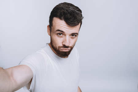 Handsome young man in white shirt doing selfieの写真素材