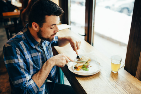 Handsome young man having lunch in cosy restaurant aloneの写真素材