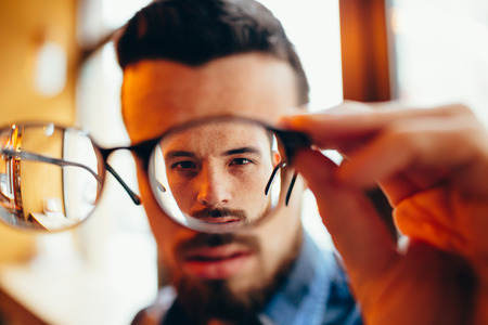 Closeup portrait of young man with glasses, who has eyesight problemsの写真素材